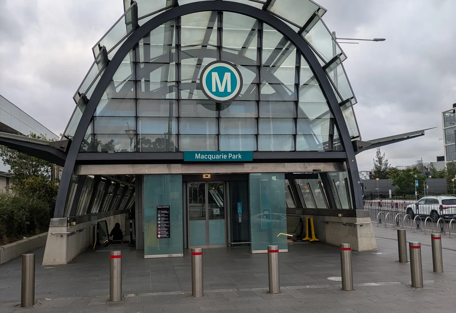 The main entrance of Macquarie Park Metro station, with commuters and the surrounding business-park towers